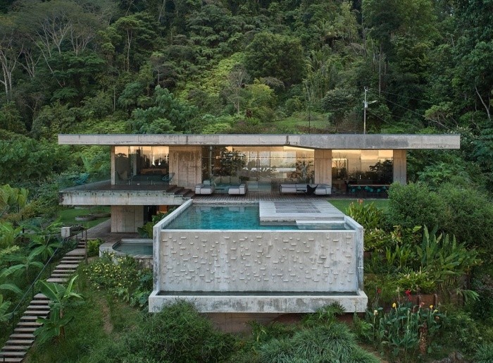Величественная бетонная вилла с выступающим бассейном среди непроходимых джунглей