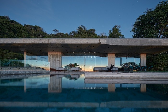 Величественная бетонная вилла с выступающим бассейном среди непроходимых джунглей